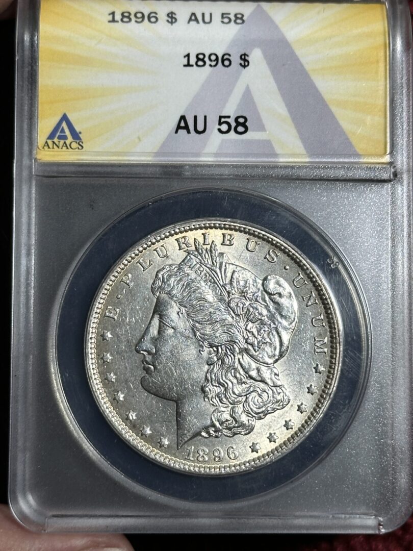 A 1896 Morgan Dollar ANACS AU58 with liberty's profile, encased in a protective anacs holder, displaying condition ratings at the top.