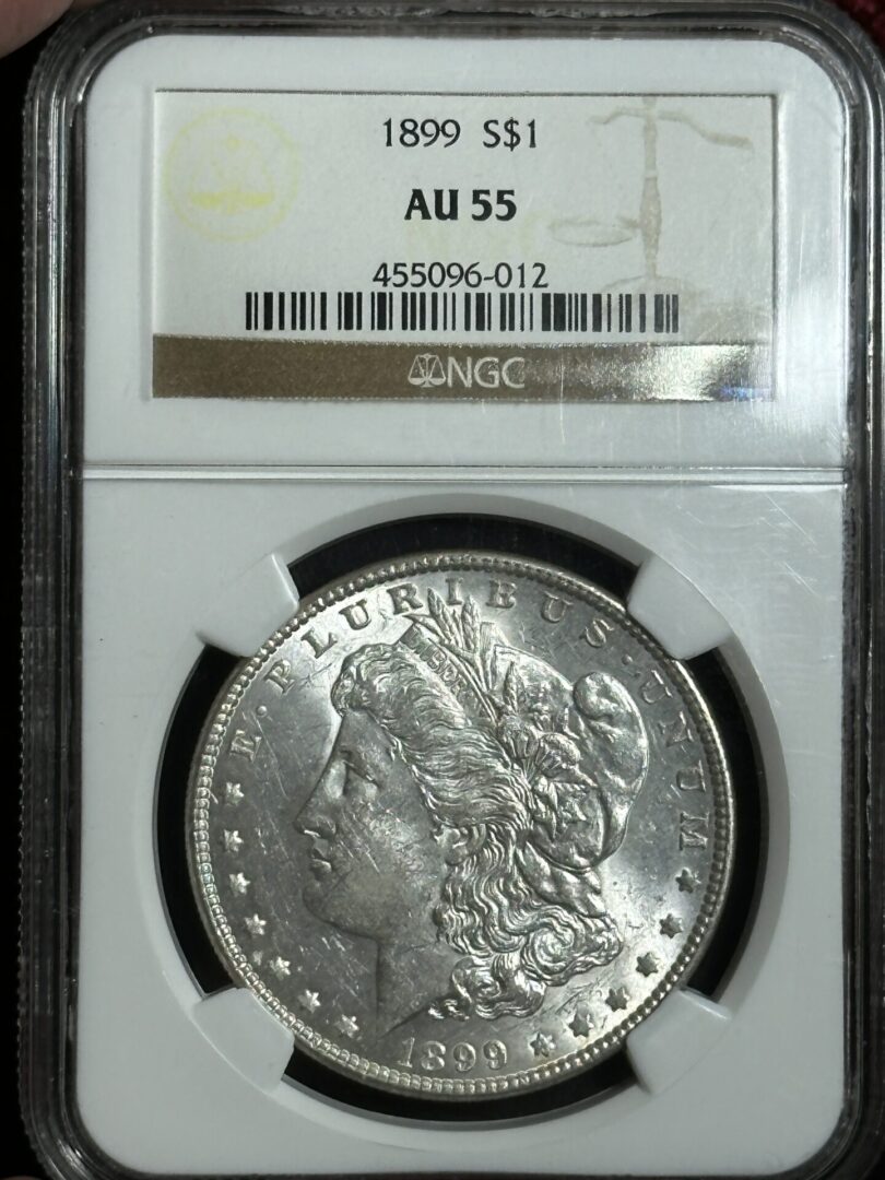 1899 Morgan Dollar NGC AU55 graded by ngc in a sealed case, showing the obverse side with liberty bust and inscriptions.