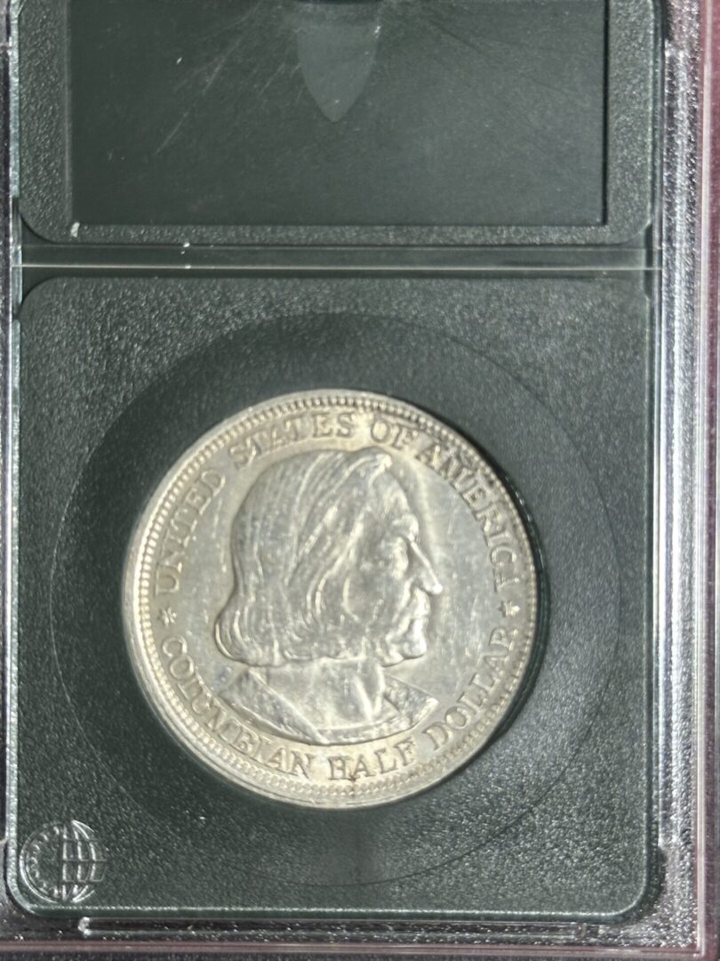 A 1893 Columbian Commemorative XF40 coin enclosed in a protective plastic case, featuring a profile image of christopher columbus.