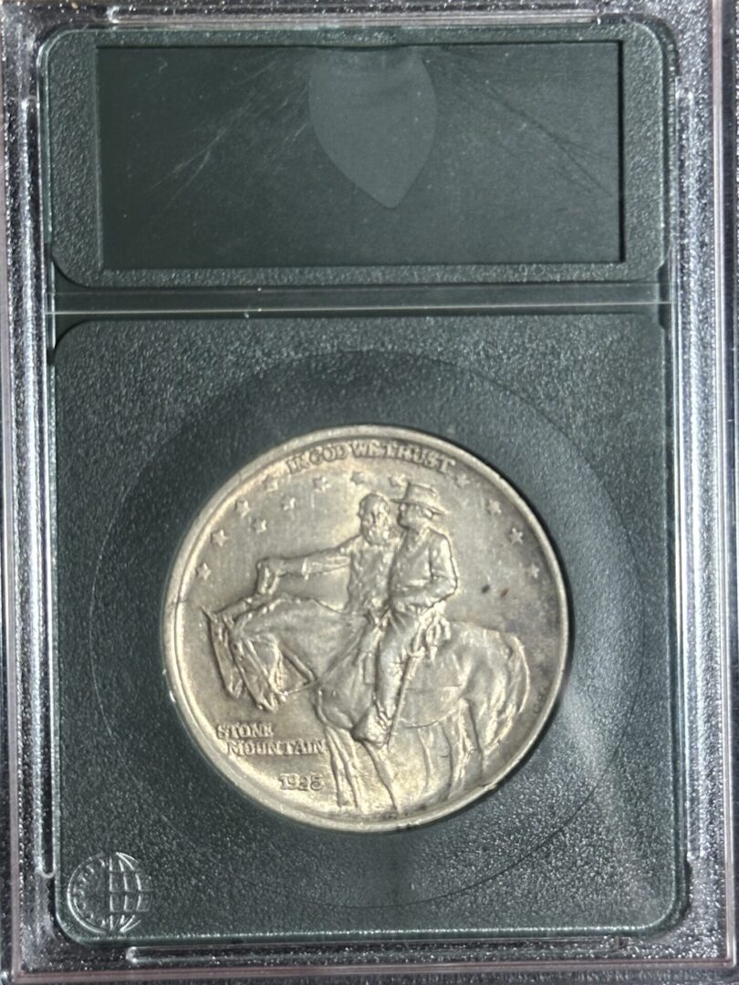 A 1925 Stone Mountain Commemorative AU58 featuring the yorktown surrender, encased in a protective clear holder with a black frame.